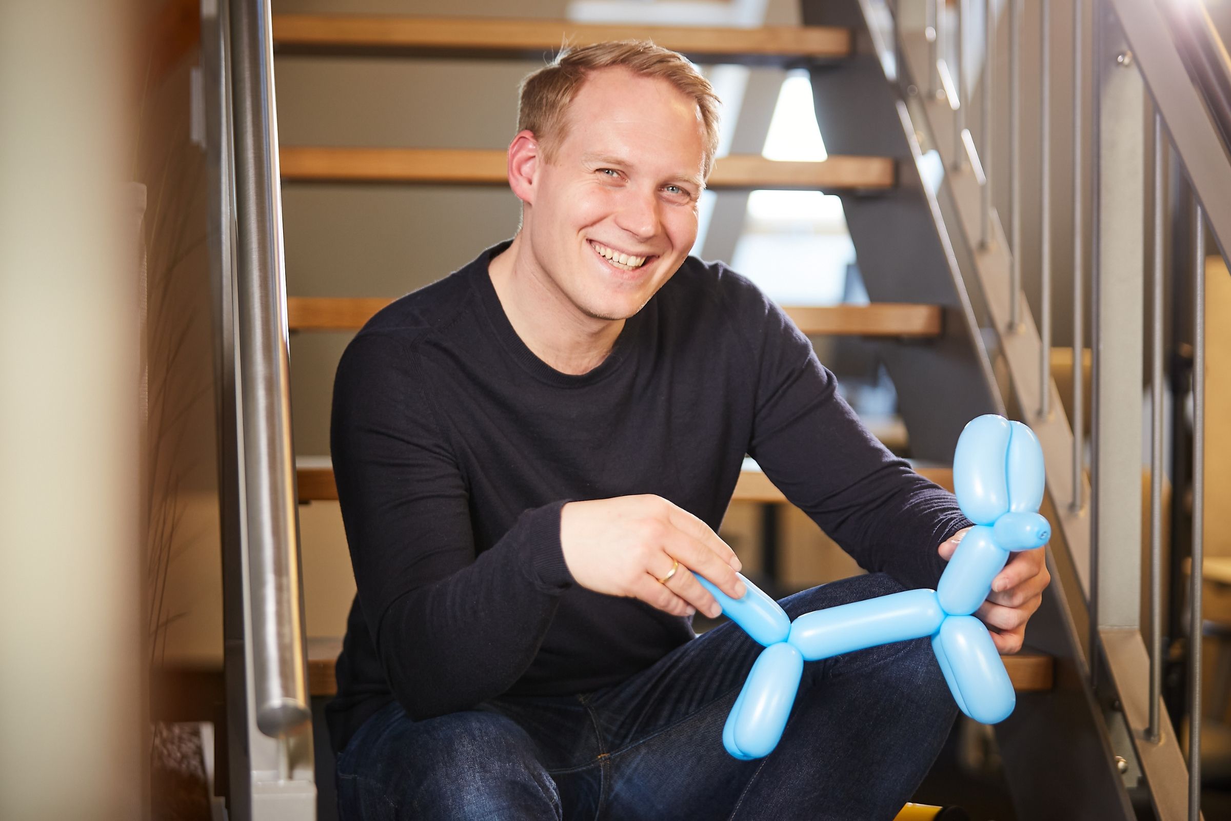 Peter Bonner smiling while holding a blue balloon dog.