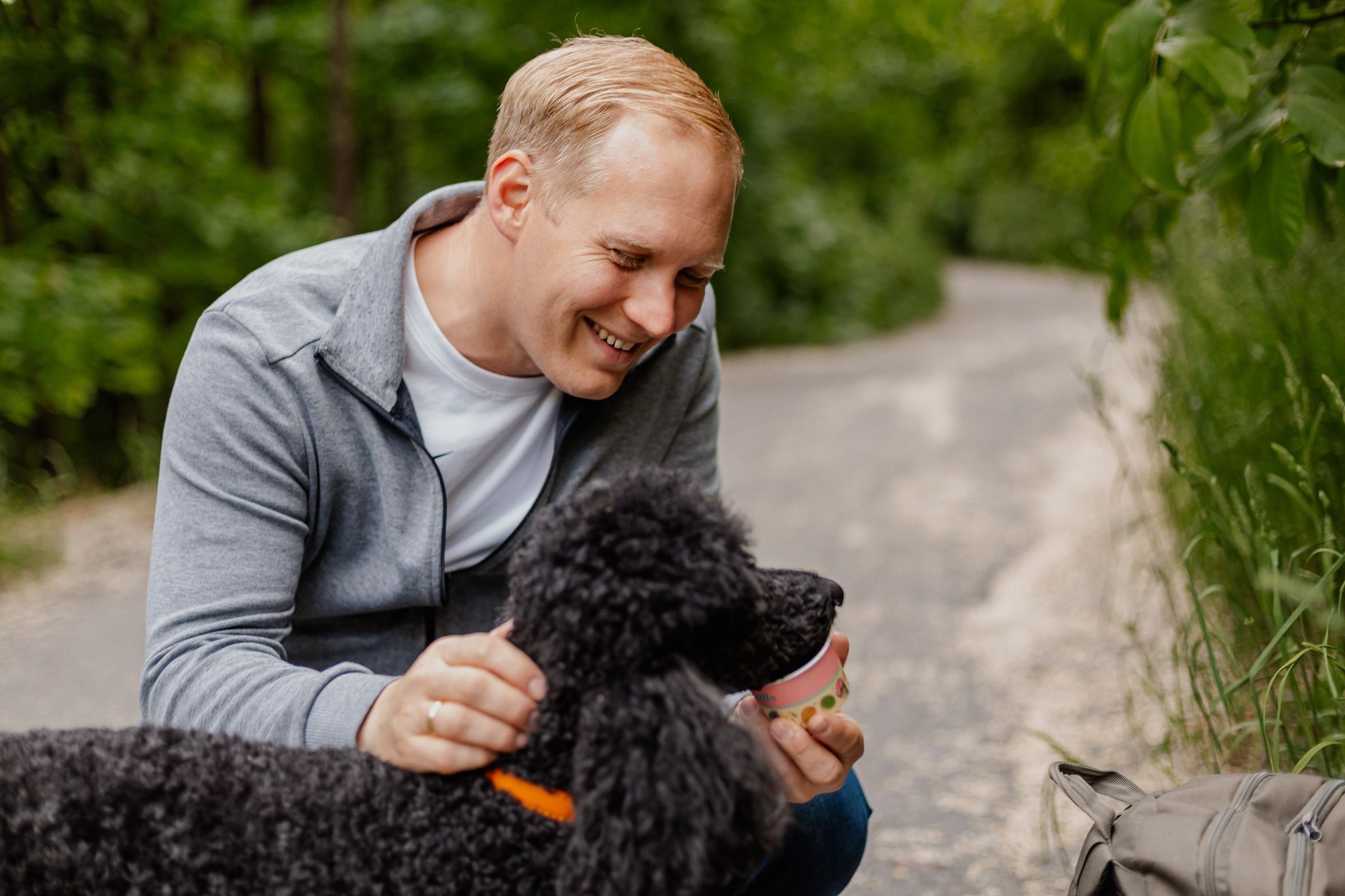 Peter Bonner with his black standard poodle Dasher in a calm everyday moment outdoors.